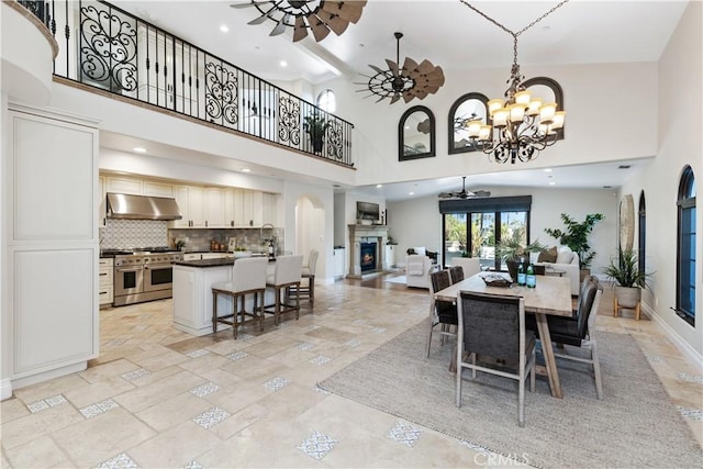 dining area with a towering ceiling and ceiling fan with notable chandelier