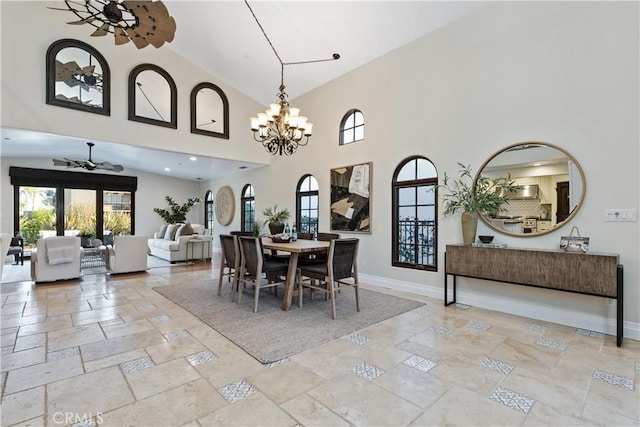 dining space featuring a towering ceiling and ceiling fan with notable chandelier