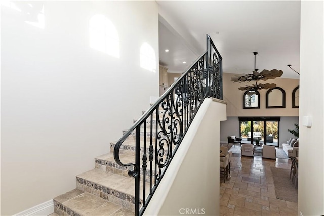 staircase with a towering ceiling and ceiling fan