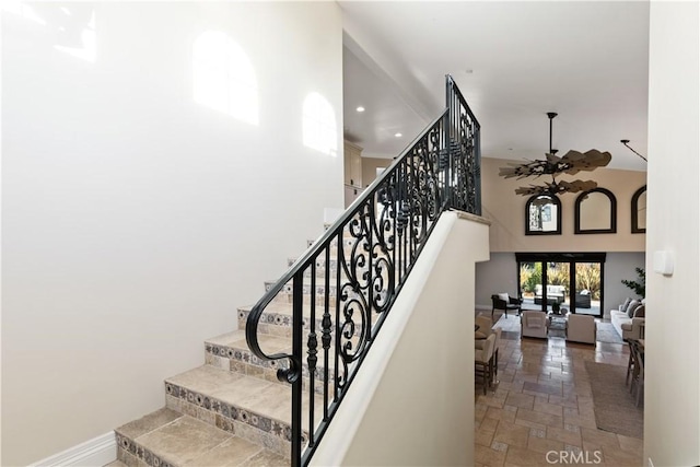 staircase with recessed lighting, stone tile flooring, a high ceiling, a ceiling fan, and baseboards