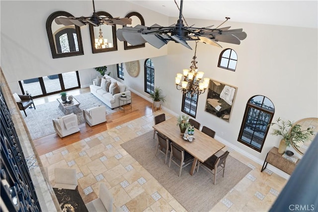 living room featuring a chandelier, high vaulted ceiling, and baseboards