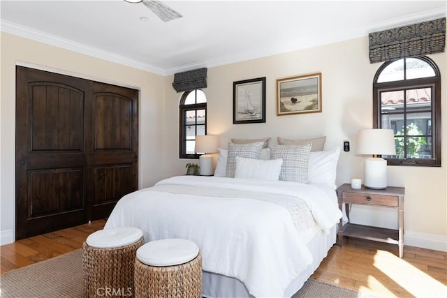 bedroom with baseboards, ornamental molding, and wood finished floors