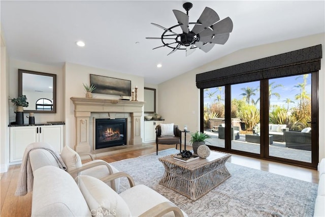 living room with ceiling fan, vaulted ceiling, and light hardwood / wood-style flooring