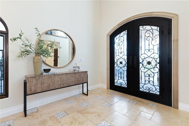 foyer entrance with baseboards, arched walkways, and french doors