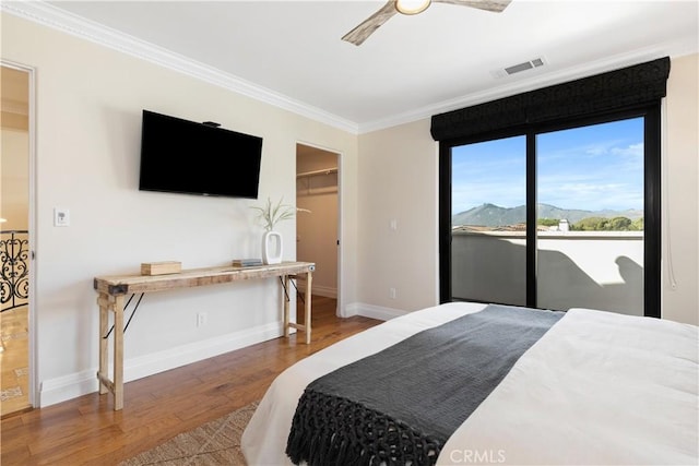 bedroom featuring wood-type flooring, a spacious closet, access to outside, ceiling fan, and crown molding