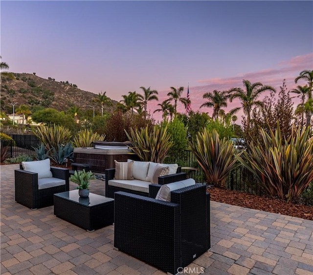 view of patio / terrace with a hot tub, fence, and outdoor lounge area