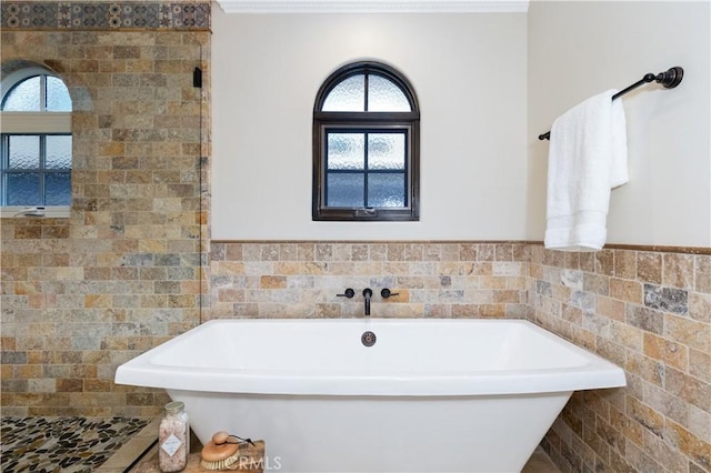 bathroom featuring a healthy amount of sunlight, tile walls, and a bathtub