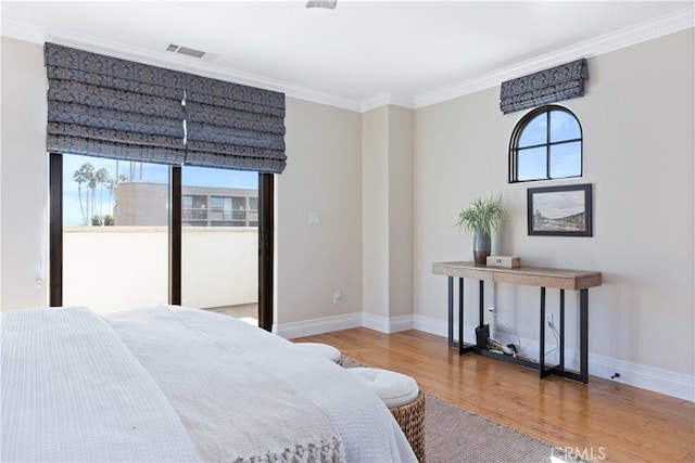 bedroom featuring multiple windows, hardwood / wood-style floors, and ornamental molding