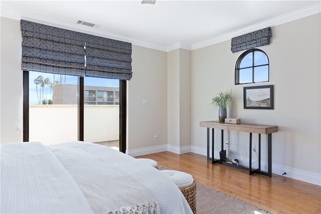 bedroom with multiple windows, crown molding, visible vents, and wood finished floors