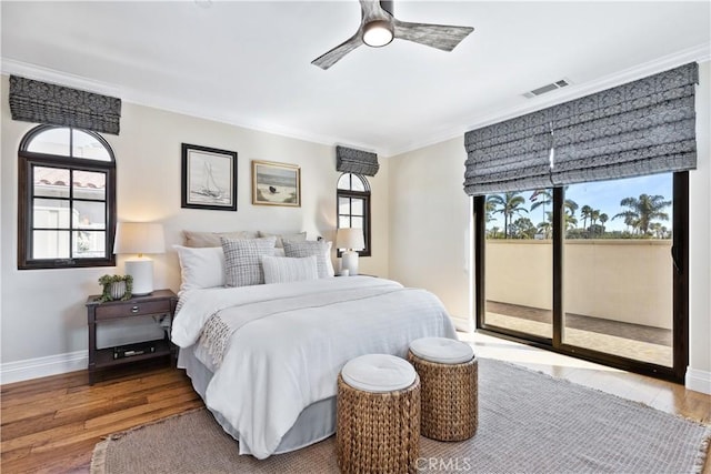 bedroom featuring multiple windows, ornamental molding, wood-type flooring, and access to outside