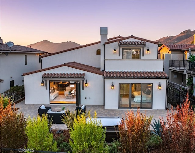 back house at dusk featuring a mountain view and a patio area