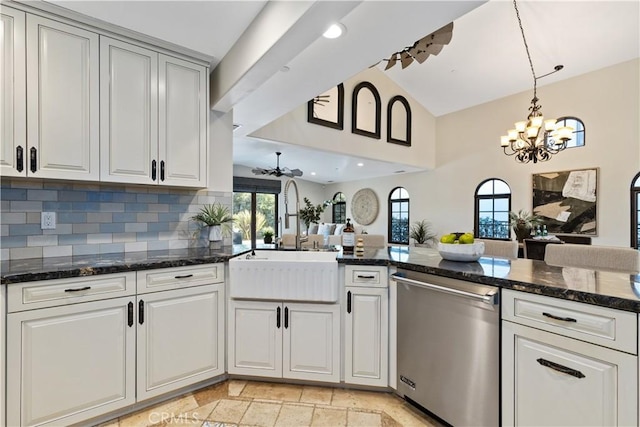 kitchen with stainless steel dishwasher, dark stone counters, kitchen peninsula, and sink