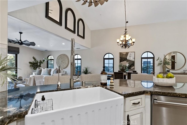 kitchen with decorative light fixtures, open floor plan, white cabinets, a sink, and ceiling fan with notable chandelier