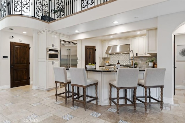 kitchen featuring white cabinetry, stainless steel appliances, a high ceiling, and backsplash