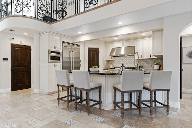 kitchen featuring dark countertops, under cabinet range hood, appliances with stainless steel finishes, and white cabinets