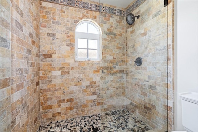 full bath featuring a tile shower and toilet