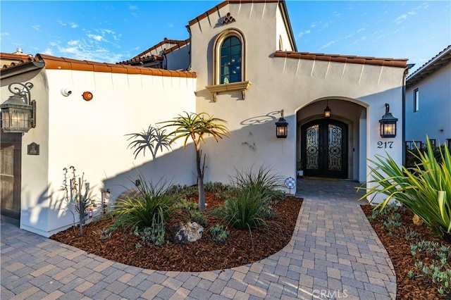 view of exterior entry featuring stucco siding and french doors