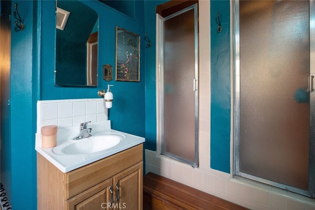 bathroom with vanity, tasteful backsplash, and a shower with shower door