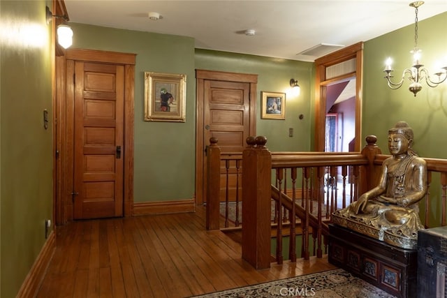 hallway with hardwood / wood-style floors and an inviting chandelier