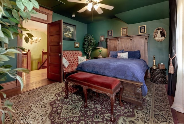 bedroom with ceiling fan with notable chandelier and hardwood / wood-style flooring