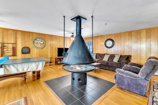 playroom featuring pool table, a wood stove, wood walls, and wood-type flooring