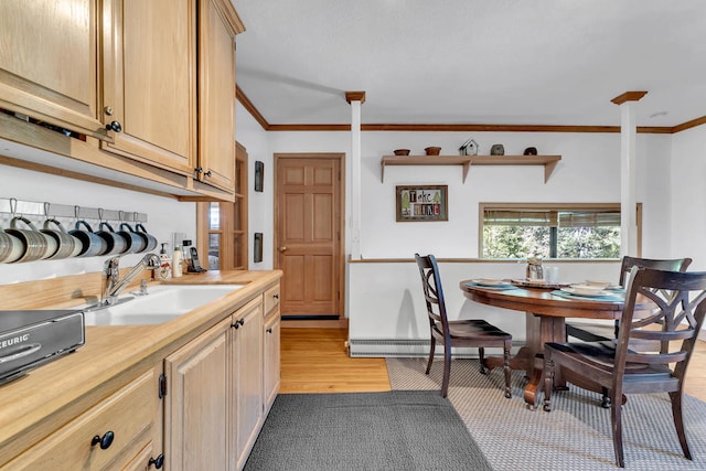 kitchen with light brown cabinetry, ornamental molding, sink, and light hardwood / wood-style floors