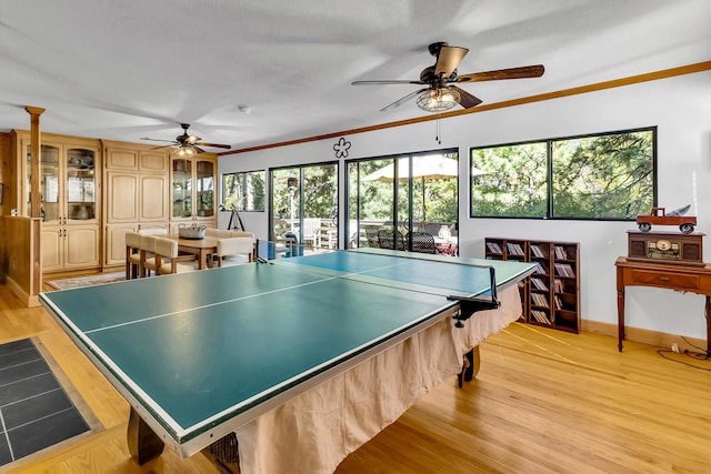 rec room featuring light hardwood / wood-style floors, ornamental molding, and ceiling fan