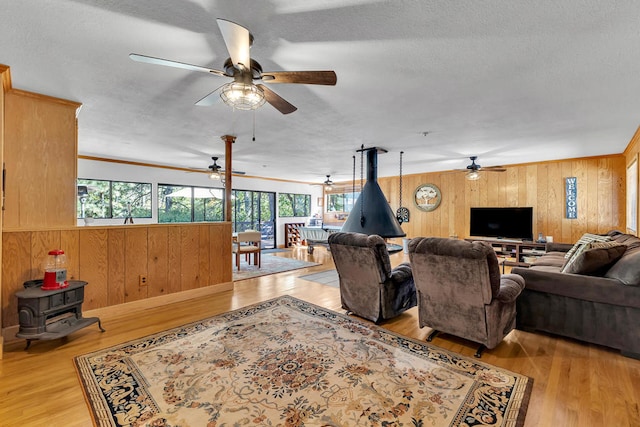 living room with wooden walls, light hardwood / wood-style floors, and a wood stove