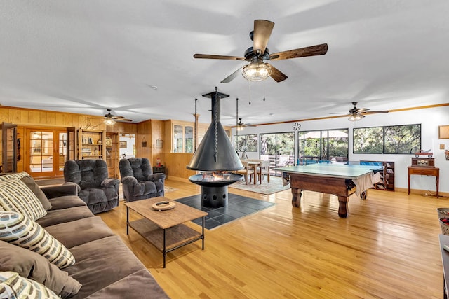 rec room with light hardwood / wood-style floors, ornamental molding, and wooden walls