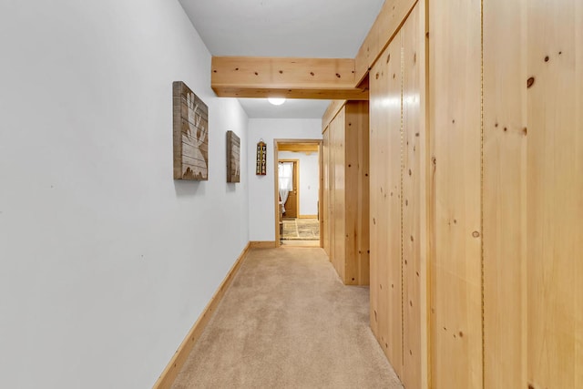 hallway featuring light carpet and beamed ceiling