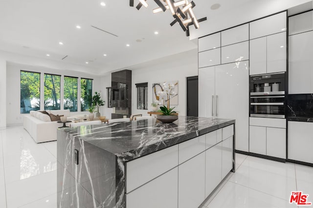 kitchen with a spacious island, white cabinetry, dark stone countertops, and light tile patterned floors