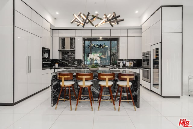 kitchen featuring backsplash, a center island, pendant lighting, white cabinets, and a breakfast bar area