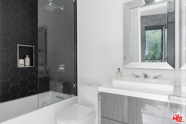 full bathroom featuring tiled shower / bath, vanity, and toilet