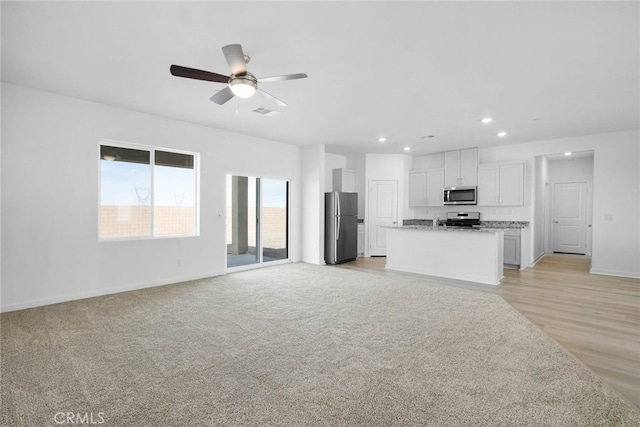 unfurnished living room with light hardwood / wood-style flooring and ceiling fan