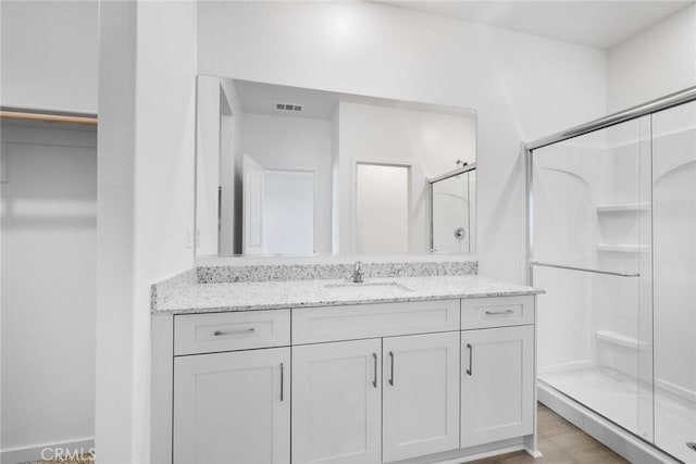 bathroom with a shower with door, vanity, and wood-type flooring