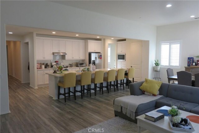 24819 Onyx Dr, Menifee, CA 92585 - kitchen featuring stainless steel refrigerator with ice dispenser, under cabinet range hood, stove, a kitchen bar, and white cabinetry