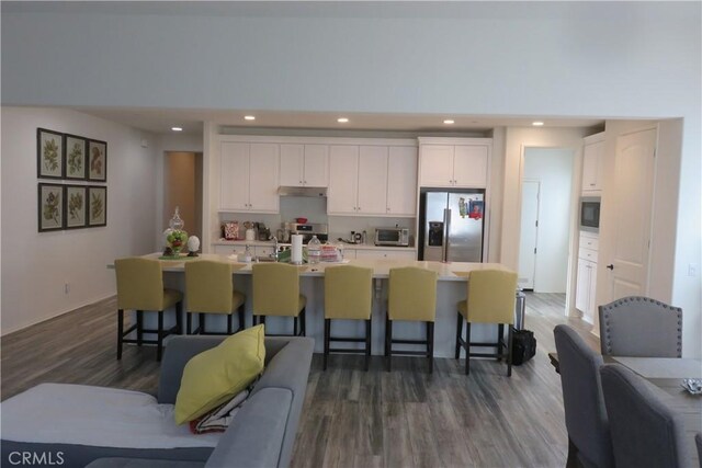 24819 Onyx Dr, Menifee, CA 92585 - kitchen featuring stainless steel appliances, under cabinet range hood, white cabinetry, a kitchen bar, and recessed lighting