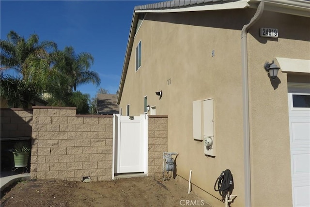 24819 Onyx Dr, Menifee, CA 92585 - view of side of property featuring a gate, stucco siding, and fence