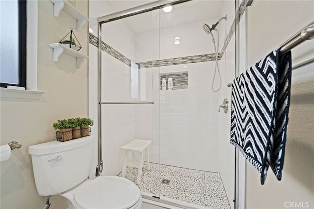 bathroom featuring a shower with door and toilet