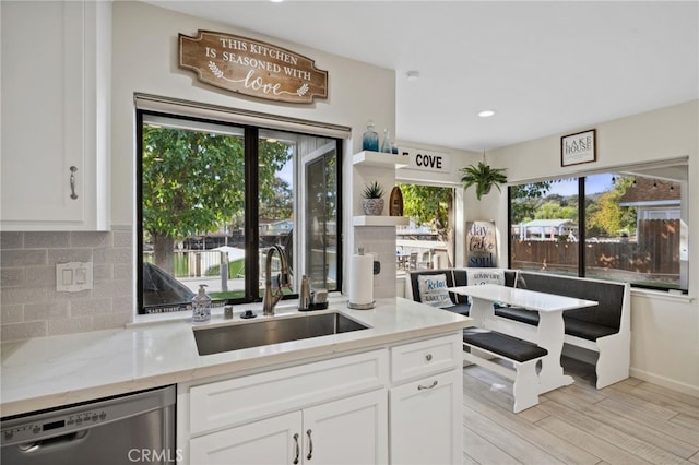 kitchen with stainless steel dishwasher, sink, plenty of natural light, and white cabinets