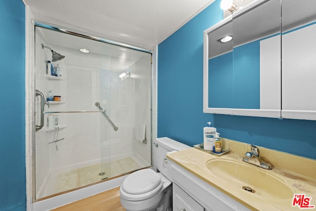 bathroom with vanity, toilet, wood-type flooring, and a shower with door