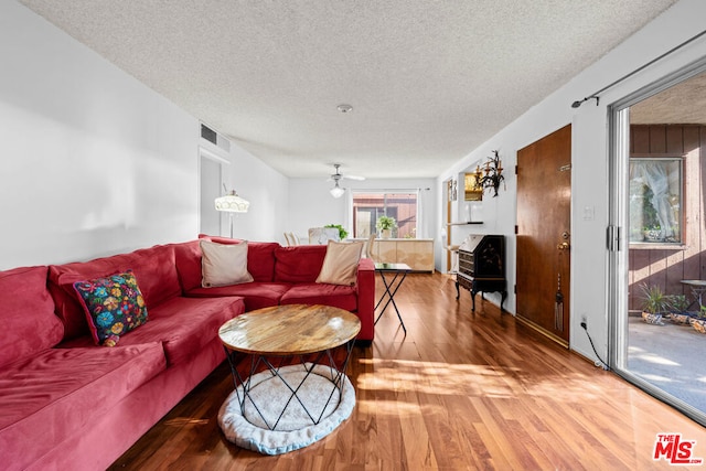 living room featuring wood-type flooring, a textured ceiling, and ceiling fan