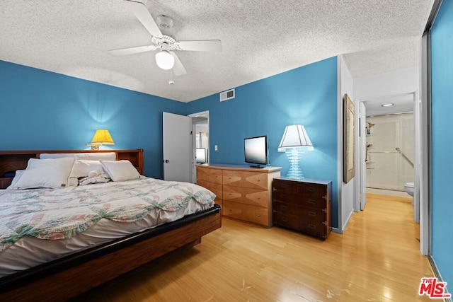 bedroom with ceiling fan, a textured ceiling, connected bathroom, and light hardwood / wood-style flooring