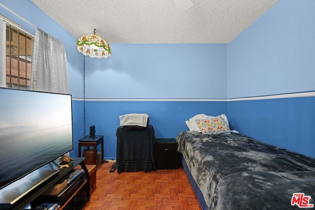 bedroom featuring parquet flooring and a textured ceiling