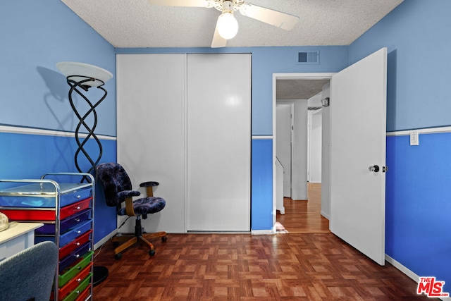 playroom with ceiling fan, dark parquet floors, and a textured ceiling