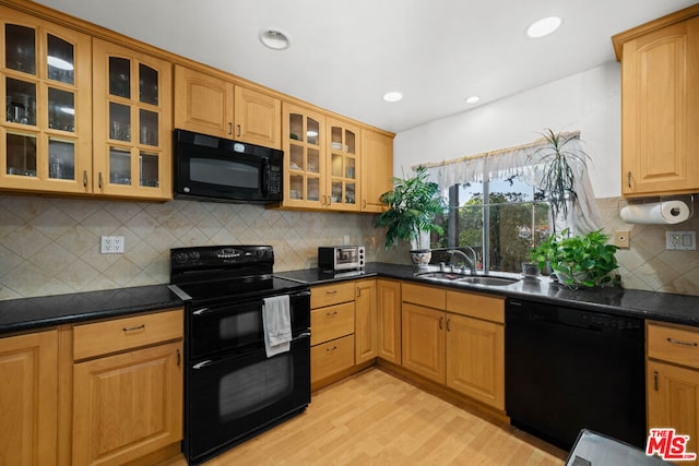 kitchen with black appliances, decorative backsplash, sink, and light hardwood / wood-style flooring