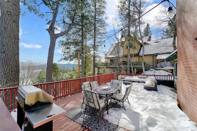 snow covered deck with a mountain view and grilling area