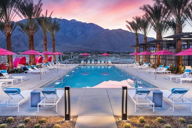 pool at dusk featuring a patio area and a mountain view