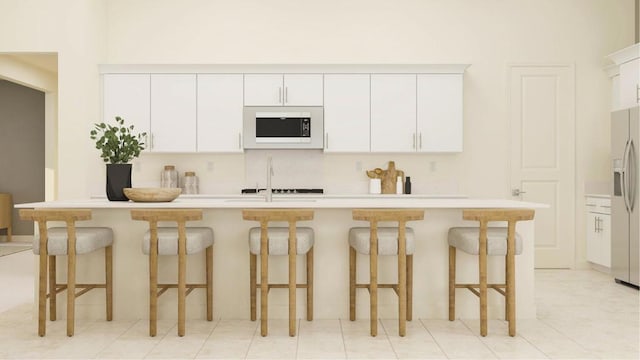 kitchen featuring white cabinets, a kitchen breakfast bar, white microwave, and stainless steel fridge with ice dispenser