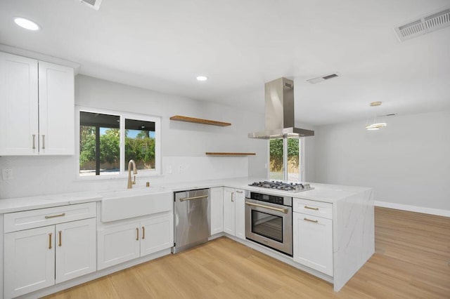 kitchen with white cabinets, a healthy amount of sunlight, stainless steel appliances, and island range hood